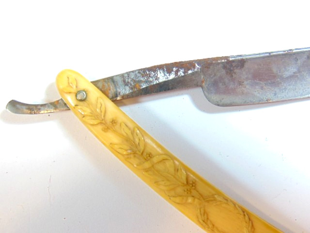 old straight razor with ornately decorated handle labeled ABS Warranted