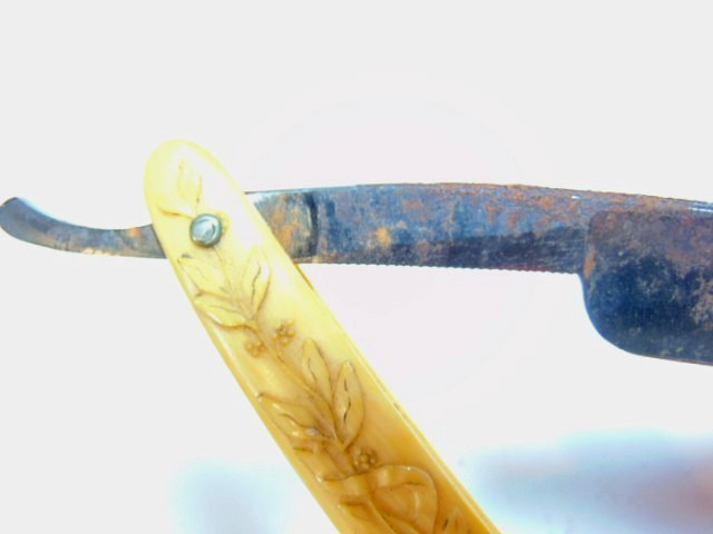 old straight razor with ornately decorated handle labeled ABS Warranted
