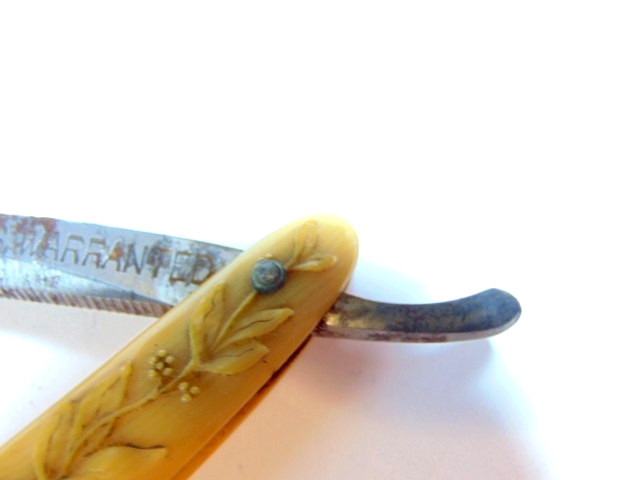 old straight razor with ornately decorated handle labeled ABS Warranted