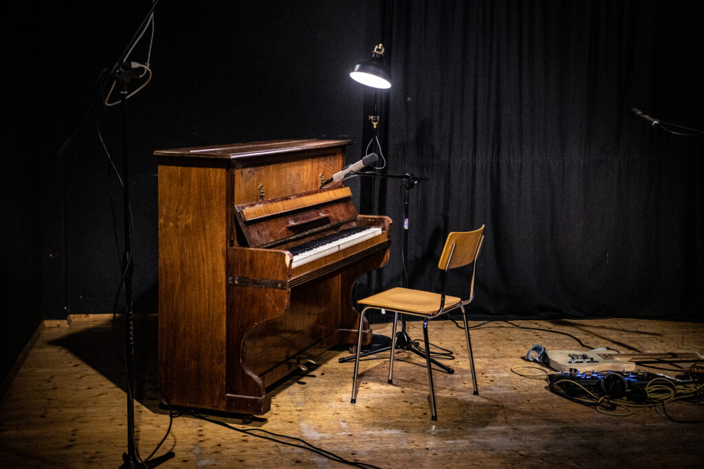 Ein Klavier mit leerem Stuhl auf einer Bühne.